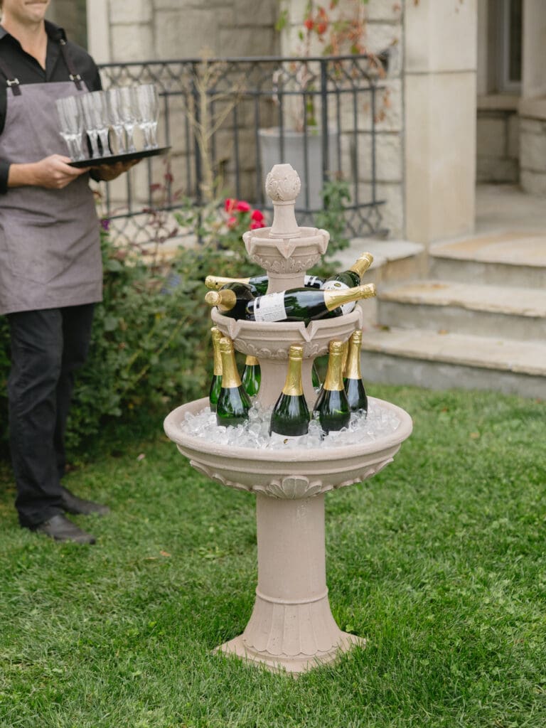 Champagne bottles displayed in a garden fountain during cocktail hour at Greystone Castle